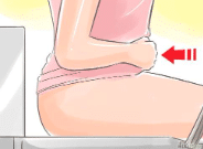 Person sitting on the toilet gently applying pressure to their abdomen to activate muscles responsible for bowel movement and proper emptying.